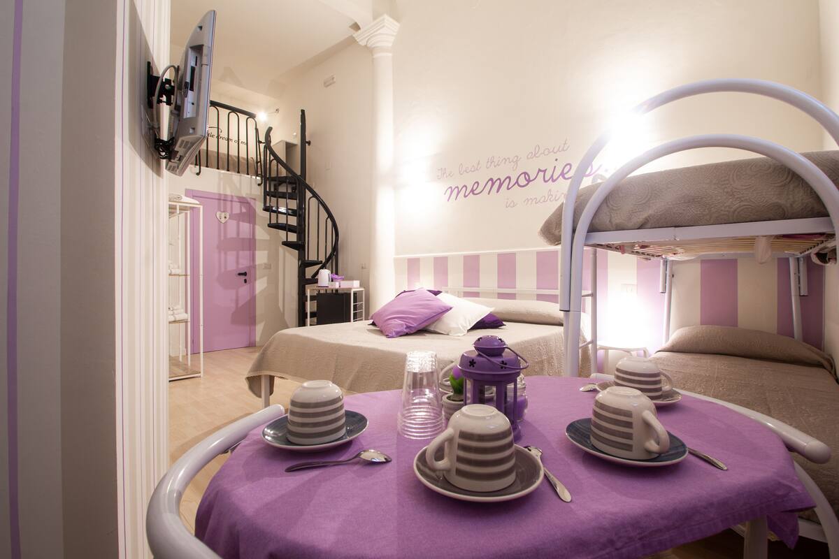 Ein Zimmer mit einem Etagenbett, einem kleinen Tisch mit Tee-Service und einer Treppe.