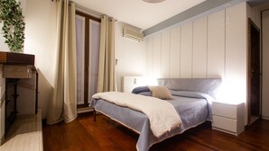 A bedroom with a bed, a nightstand, a dresser, a window with curtains, and an air conditioning unit. - B&B Patrizio (San Benedetto del Tronto)