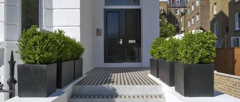 A modern building with a white facade, a black door, and a tiled entrance.