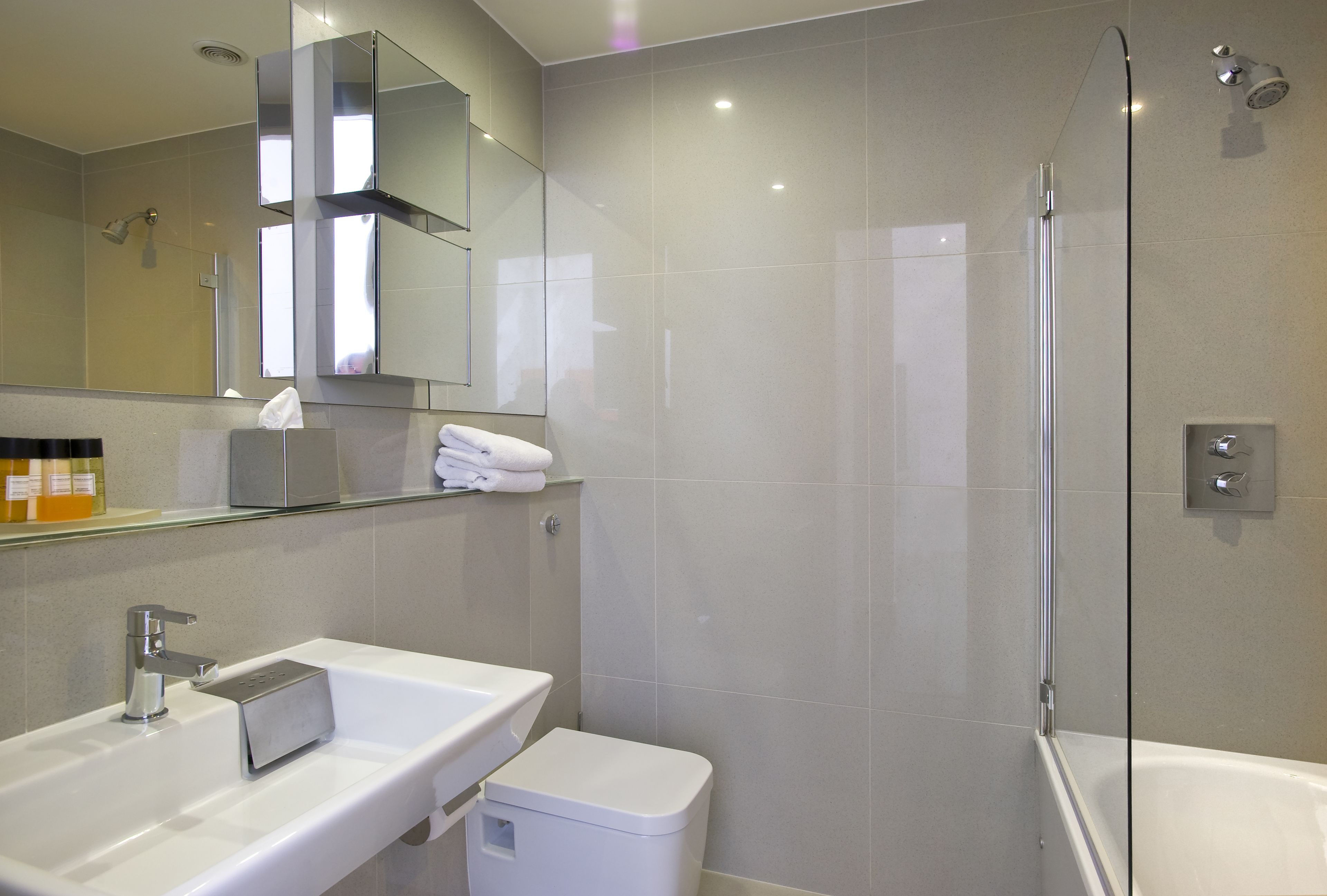 A modern bathroom with a glass-enclosed shower, a white sink, and a mirror above the sink.
