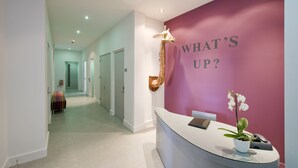 A reception area with a curved reception desk, a wall-mounted giraffe sculpture, and a potted orchid. - Templeton Place by Supercity Aparthotels (London)
