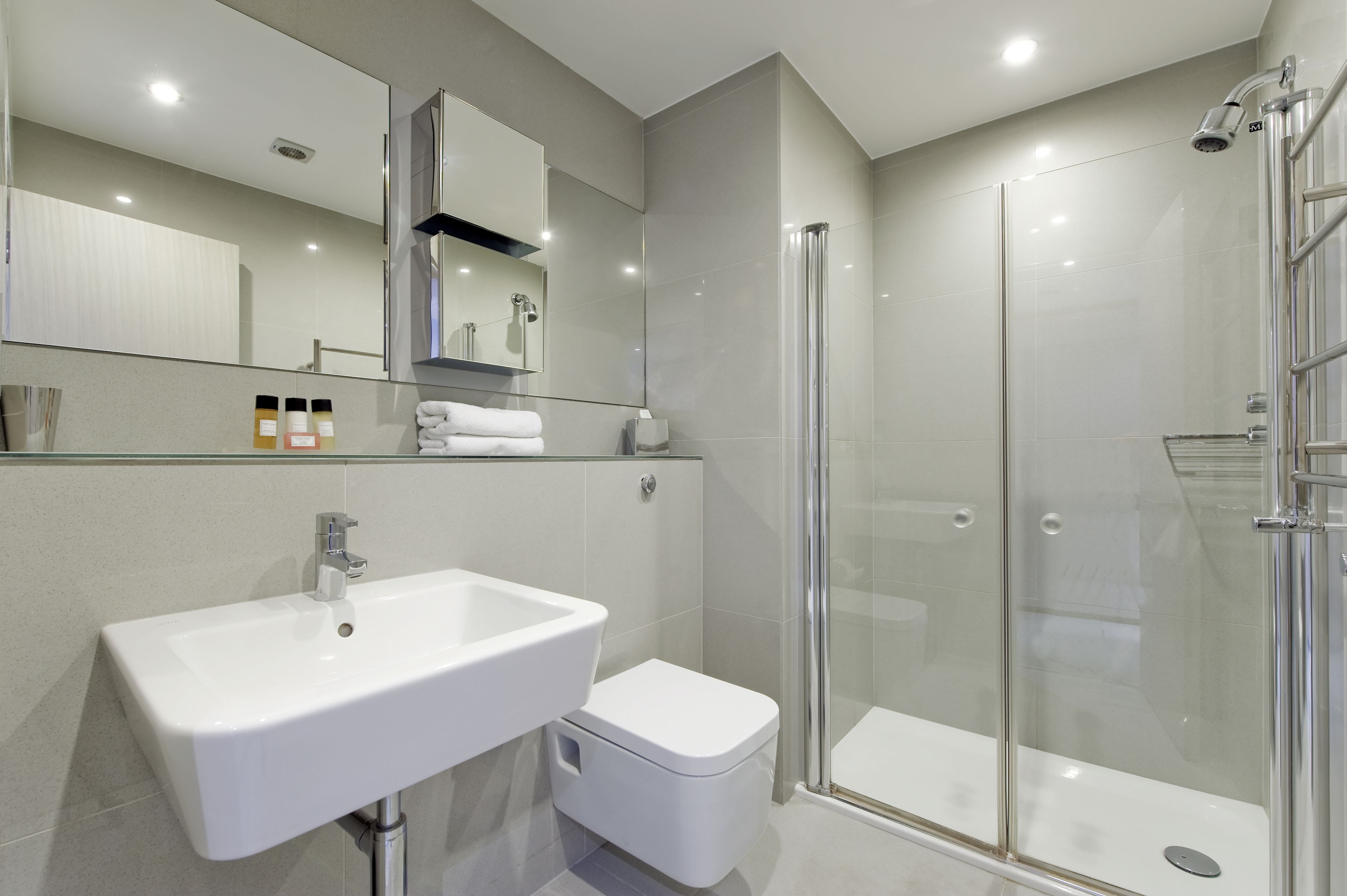 A modern bathroom with a white sink, toilet, and glass shower enclosure.