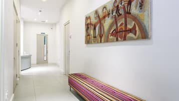 A hallway with a colorful bench, a reception desk, and a large abstract painting on the wall.