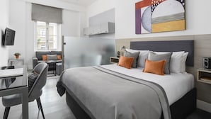 A modern hotel room with a large bed, a desk, and a sofa. - Templeton Place by Supercity Aparthotels (London)