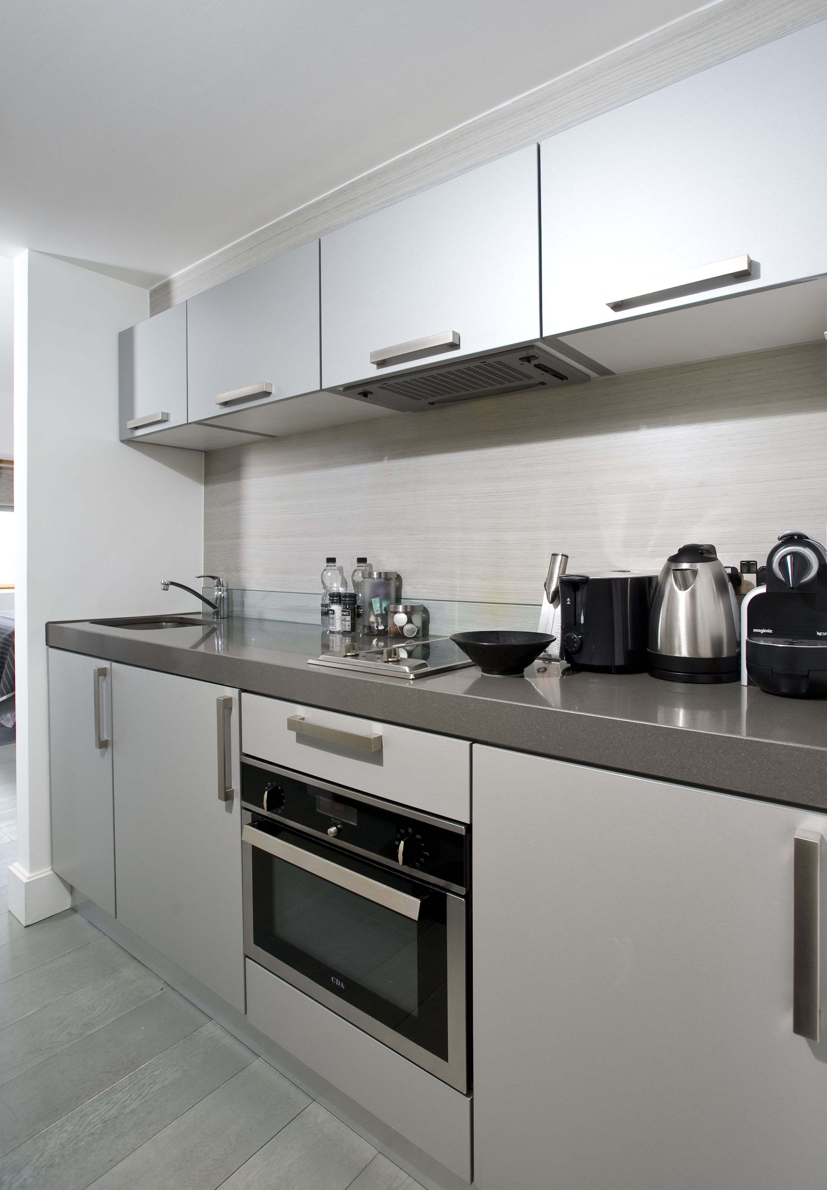 A modern kitchen with stainless steel appliances, a built-in oven, and a coffee maker.
