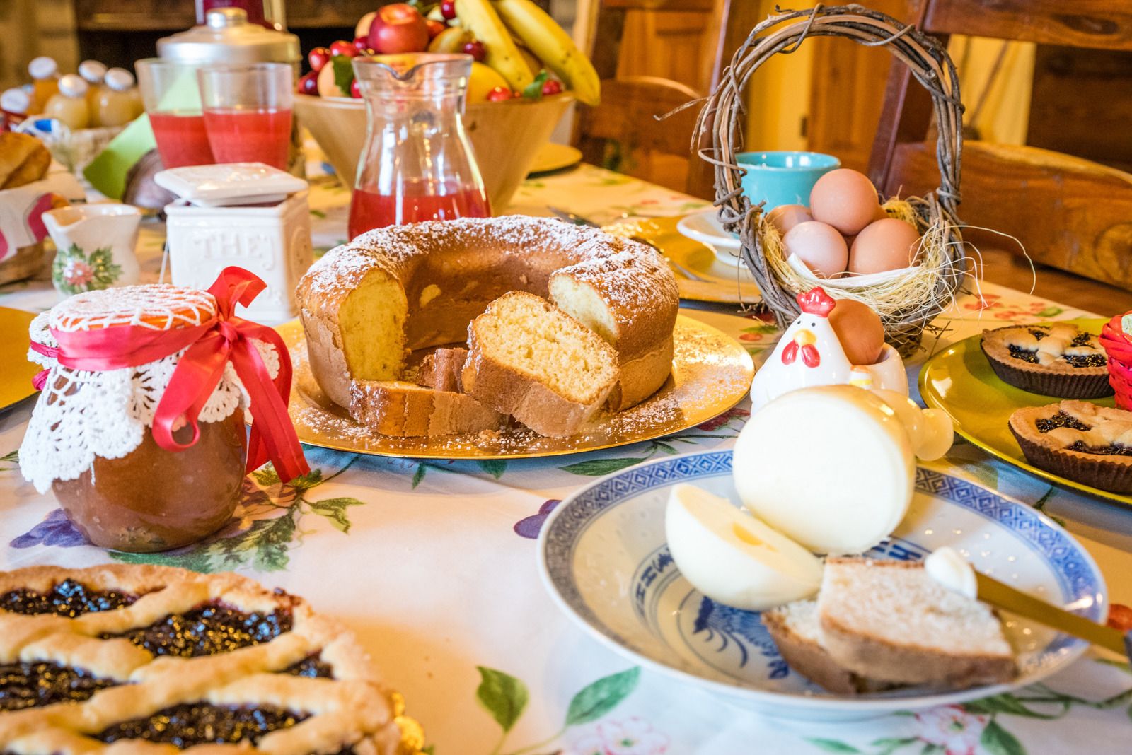 A table with various food items, including a bundt cake, eggs, and a jar of jam.