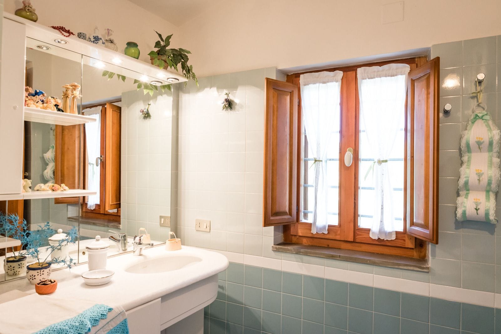 A bathroom with a white sink, mirror, and a window with wooden shutters.