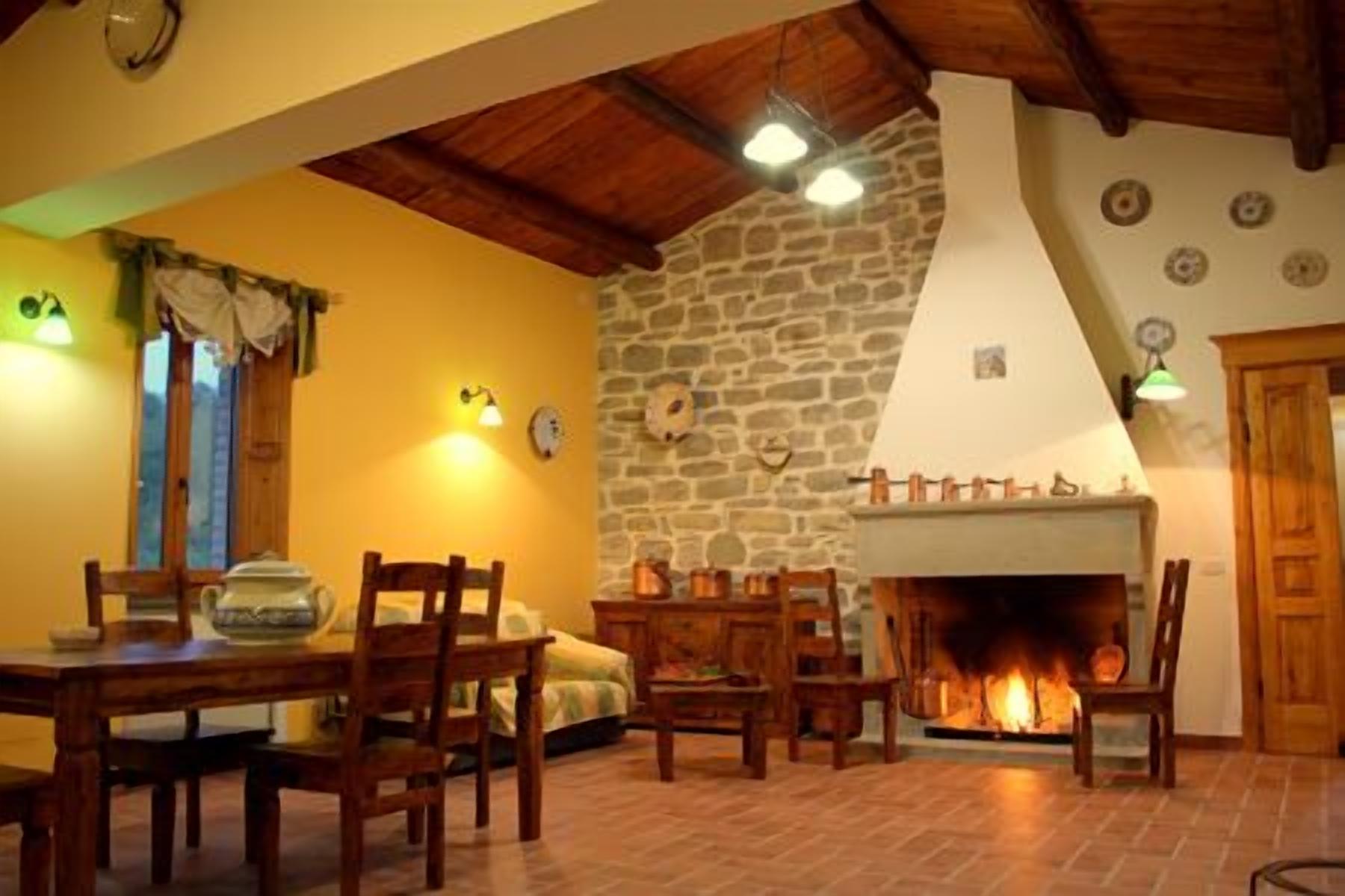 A cozy room with a stone wall, a fireplace, wooden furniture, and a dining table.