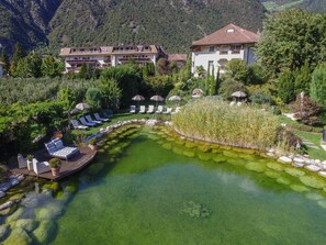 A resort with a clear pool, lounge chairs, and a mountainous backdrop. - Hotel Rössl (Parcines)