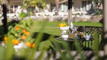 A table set outdoors with a fruit bowl, cups, and a bottle.