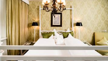 Ein Hotelzimmer mit einem Bett, zwei Nachttischlampen, einer Kristallleuchtre und einem gerahmten Bild an der Wand sowie einem grünen Kissen.