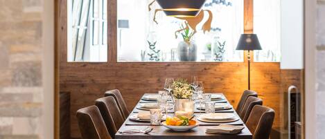 Mesa de comedor puesta con platos, vasos y un centro de flores.