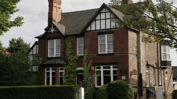 A traditional Tudor-style building with a prominent chimney, multiple windows, and a well-maintained hedge in front. - Eskdale Lodge (Sale)