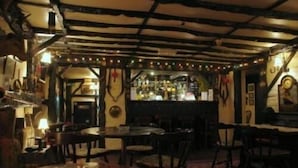 A dimly lit bar area with wooden beams on the ceiling, tables, and chairs arranged for patrons. - Eskdale Lodge (Sale)