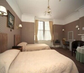Ein Hotelzimmer mit zwei Betten, einem Schreibtisch, einem Stuhl und einem Fernseher.