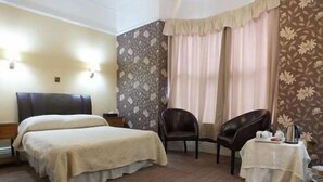 A hotel room with a bed, a chair, a small table with a tray, and a window with curtains. - Eskdale Lodge (Sale)