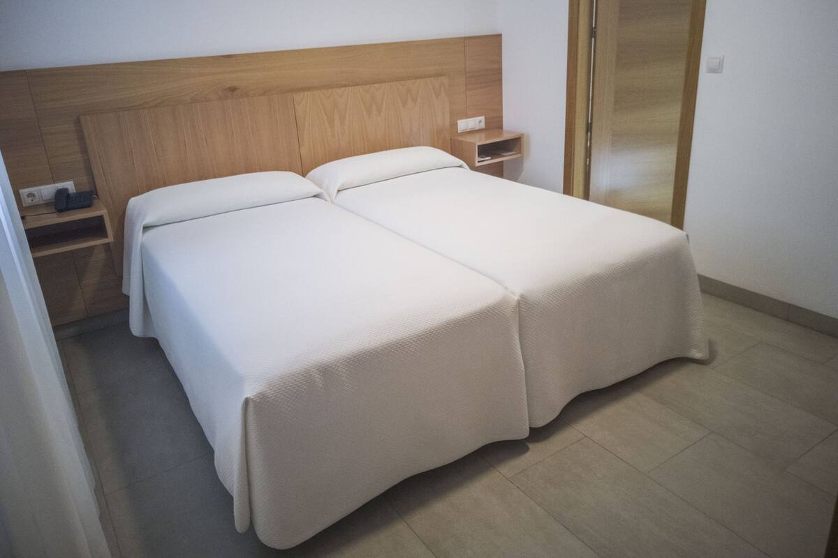 A double bed with a wooden headboard, a bedside table, and a nightstand.