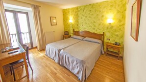 A double bed with a wooden headboard, two bedside tables, a desk with a chair, and a window with curtains. - Hotel La Casona de Jovellanos (Gijon)