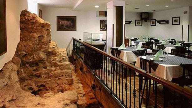 A restaurant with a stone wall feature, tables, and chairs. - Hotel La Casona de Jovellanos (Gijon)