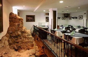 A restaurant with a stone wall feature, tables, and chairs. - Hotel La Casona de Jovellanos (Gijon)