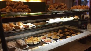 Un bufé con diversos productos de panadería y sándwiches.