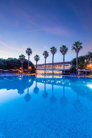 A swimming pool with palm trees and a building in the background. - Vibra Blanc Palace Aparthotel (Ciutadella de Menorca)
