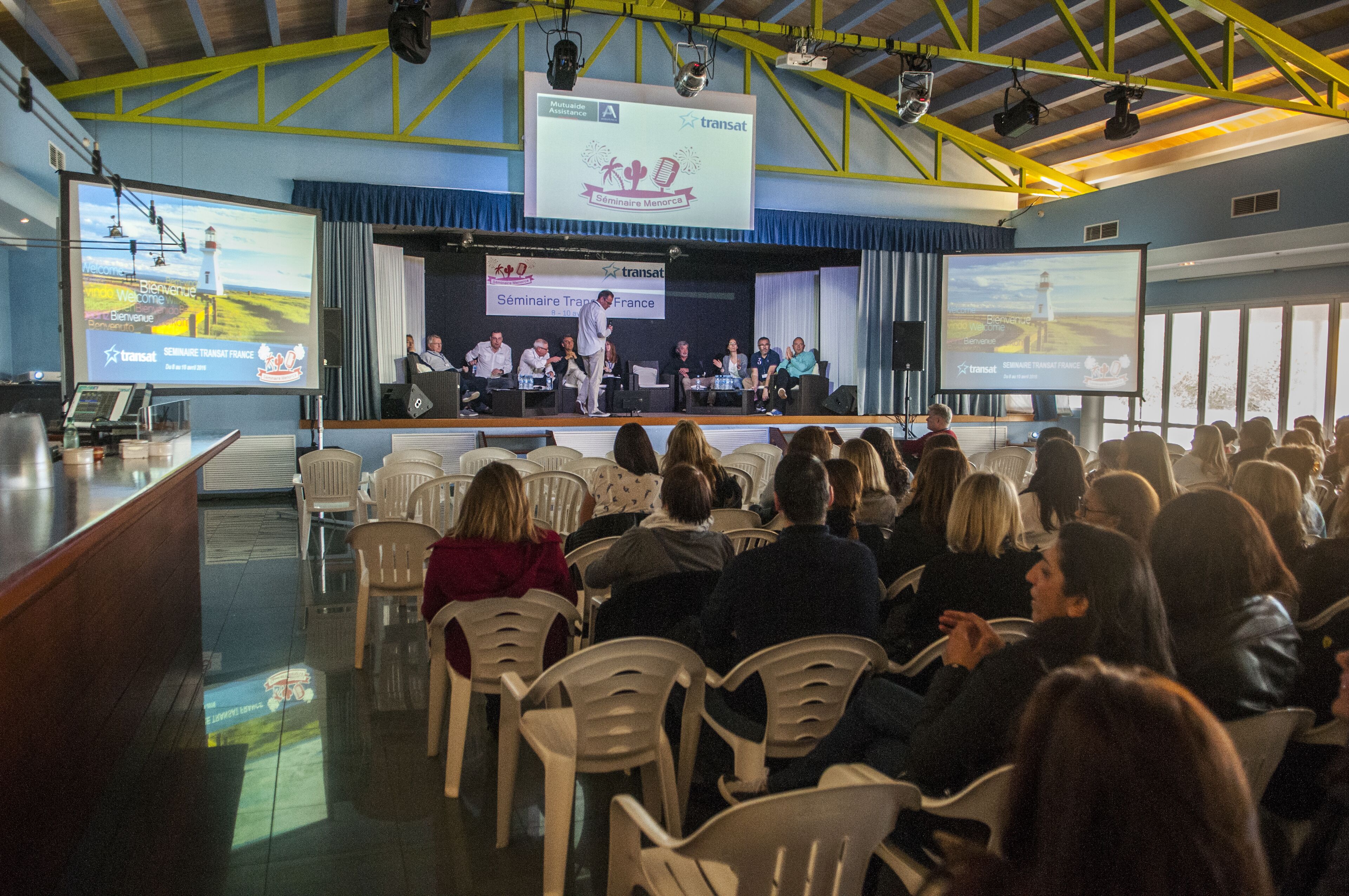 Une salle de conférence équipée d’une scène, de sièges pour le public et d’écrans de présentation.