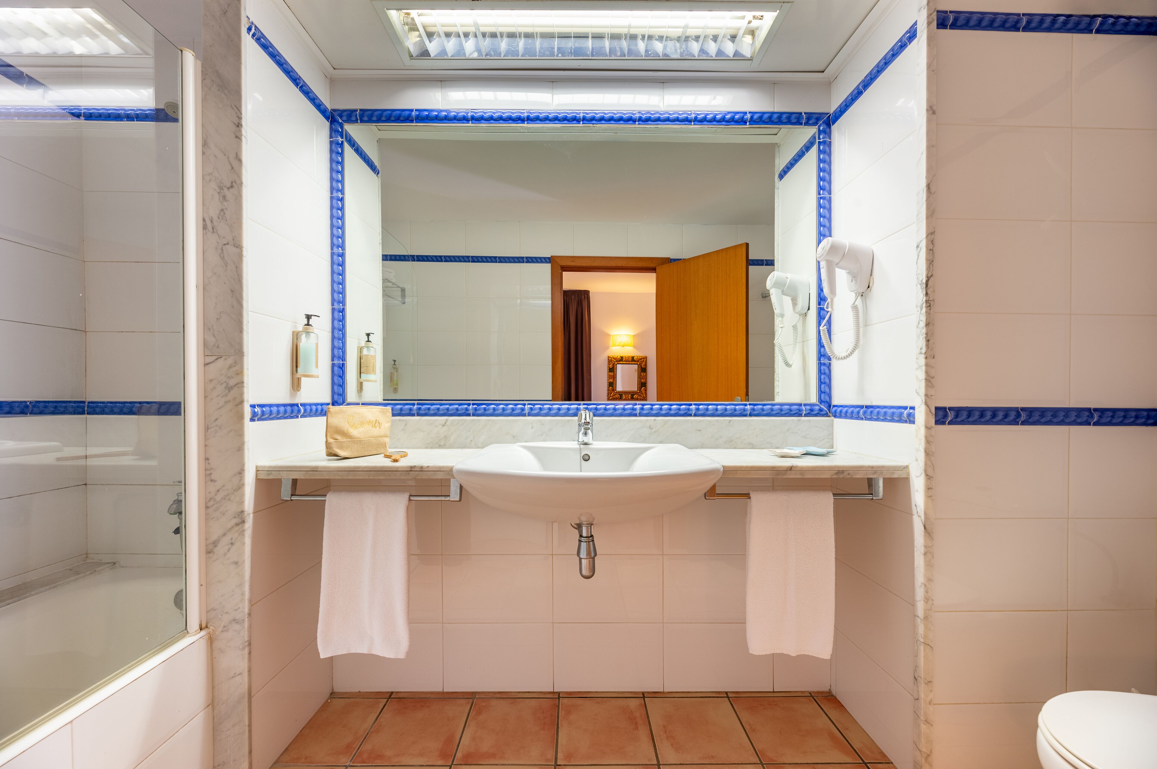Un baño con un espejo grande, un lavabo y un inodoro.