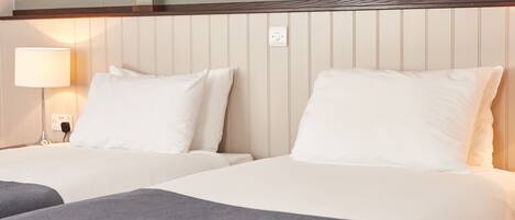 A hotel room with two beds, a nightstand with a lamp, and a wall with a dragonfly design.