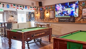 A billiards room with two pool tables, a dartboard, and a television displaying a sports event. - Corner House Hotel by Greene King Inns (Newcastle-upon-Tyne)