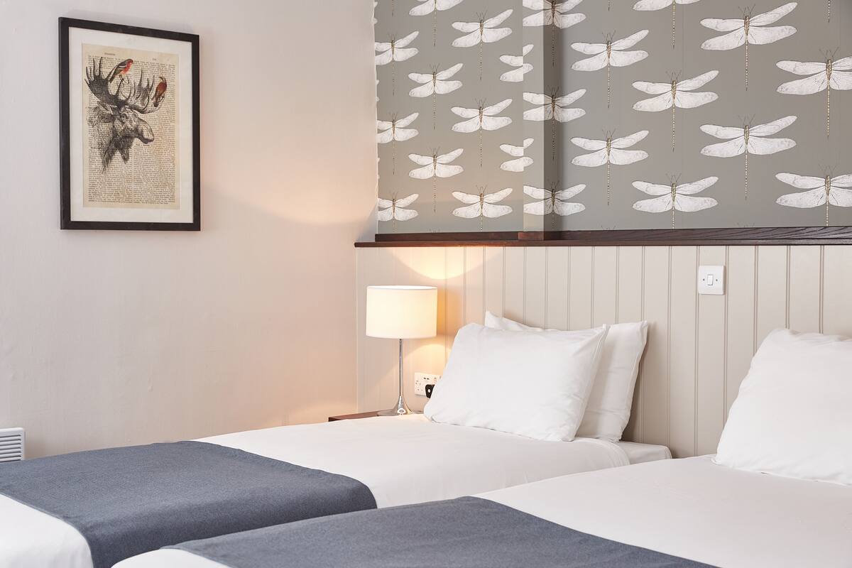 Une chambre d’hôtel avec deux lits, une œuvre d’art encadrée au mur et un papier peint à motifs.