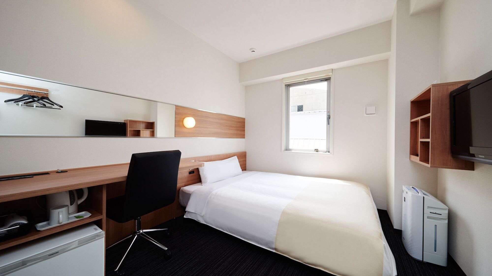 Habitació d'hotel amb un llit, escriptori, cadira, televisió i finestra.