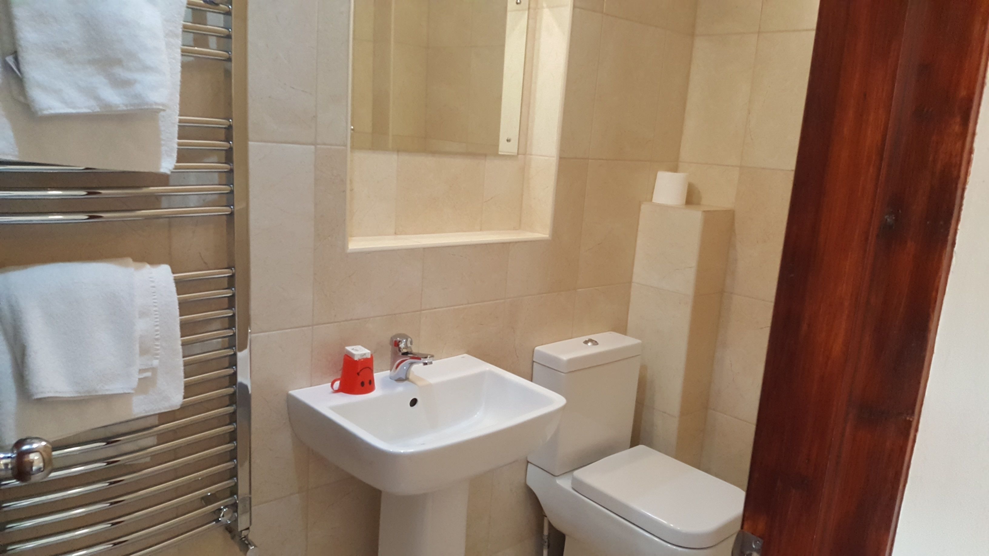 A bathroom with a white sink, a toilet, and a towel rack with white towels.