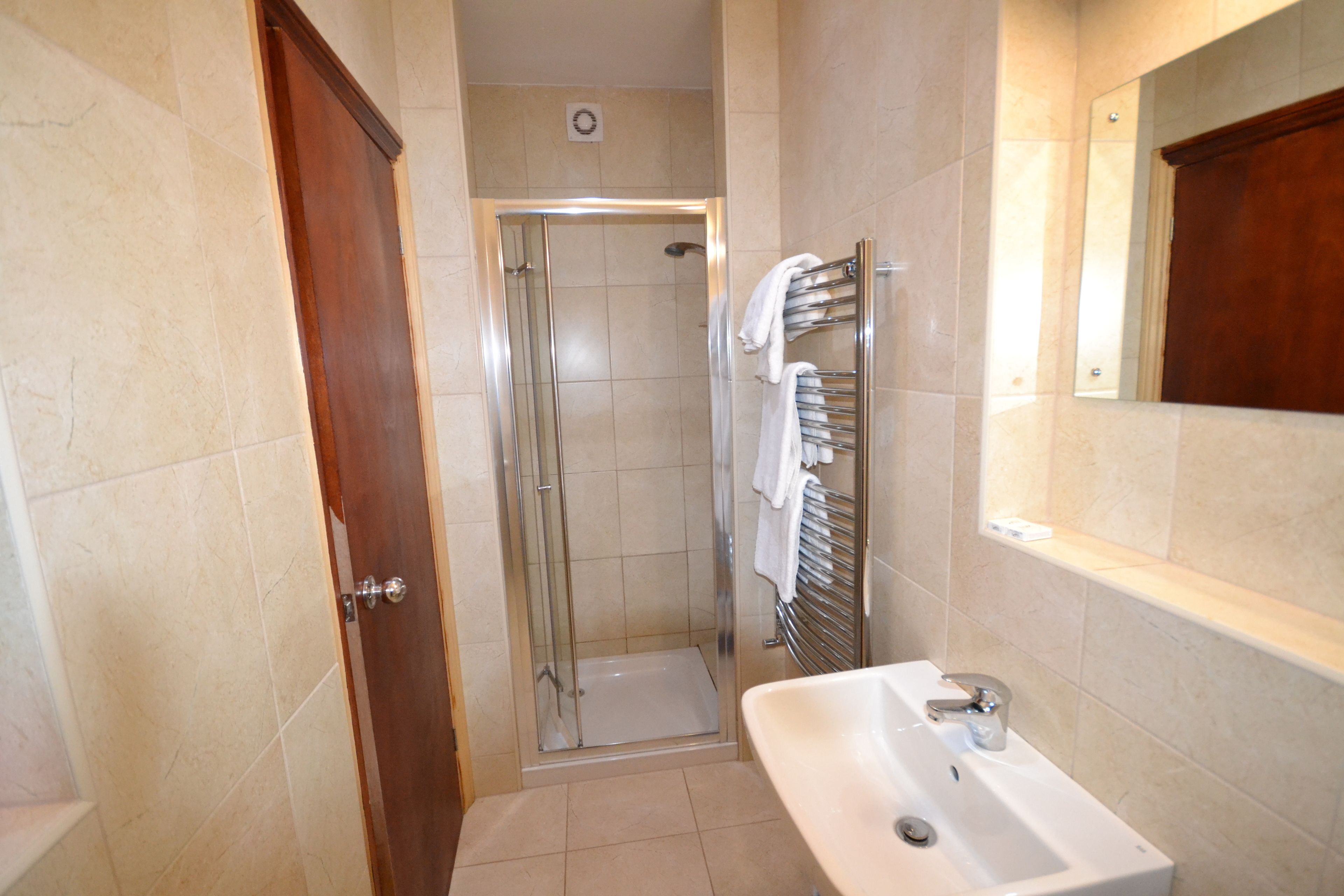 A bathroom with a glass-enclosed shower, a sink, and a towel rack.