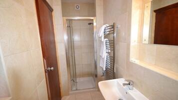 A bathroom with a glass-enclosed shower, a sink, and a towel rack.