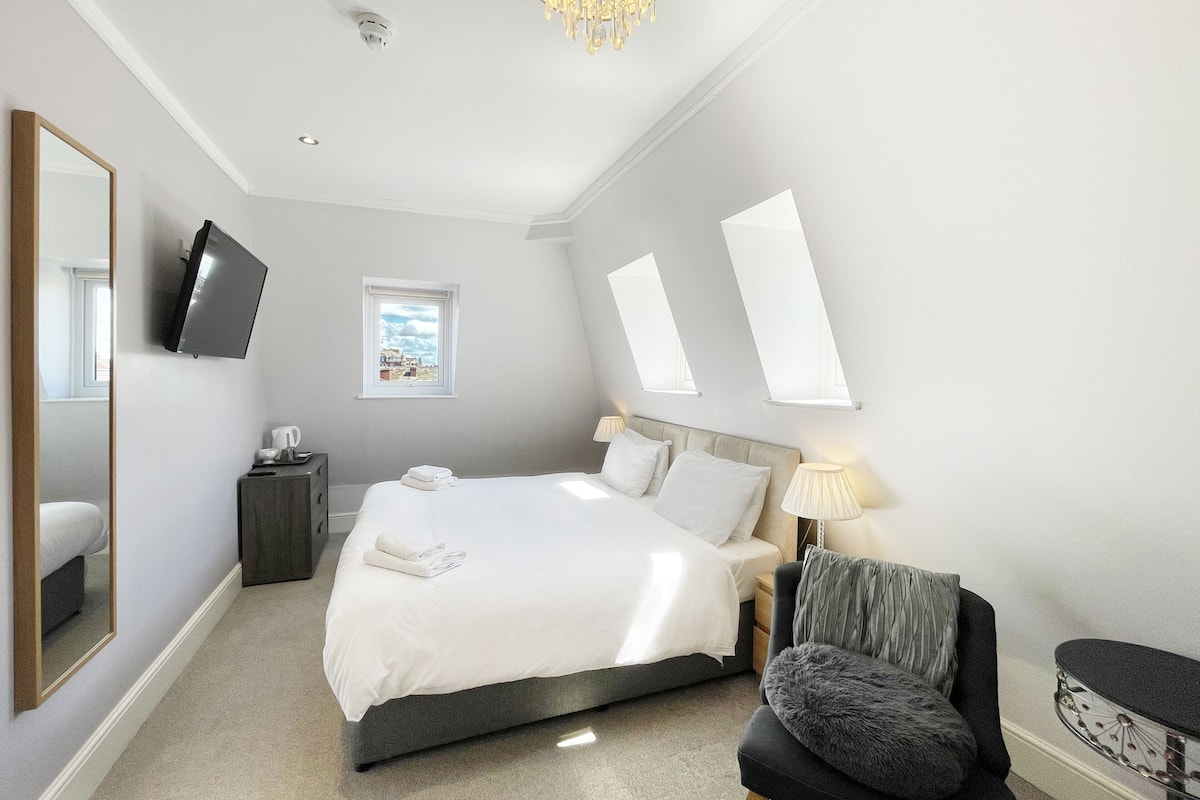 A modern bedroom with a bed, bedside tables, a chair, and a TV.