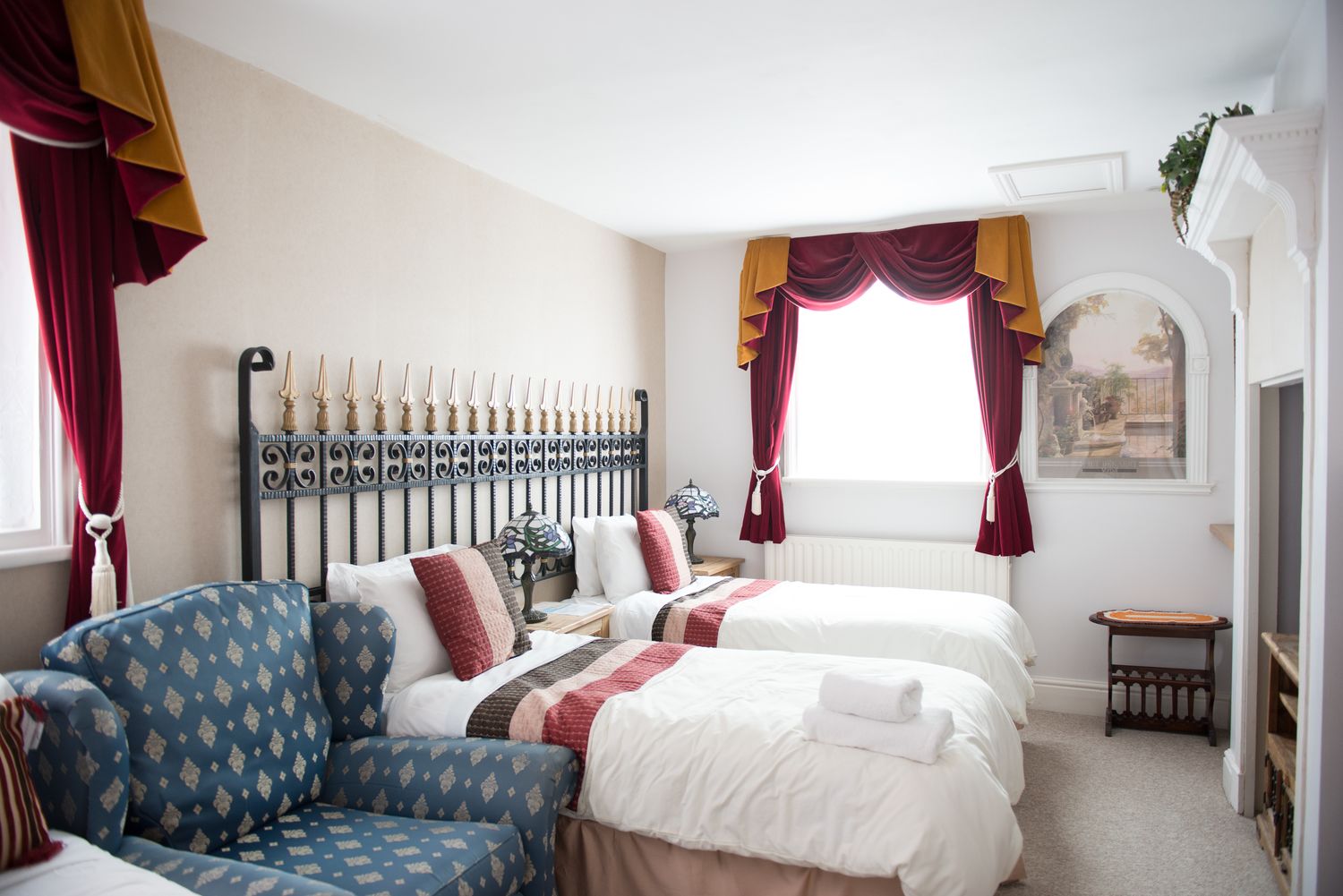 A hotel room with two beds, a sofa, and a decorative headboard.