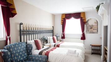 A hotel room with two beds, a sofa, and a decorative headboard.