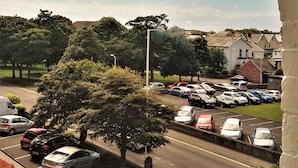 A parking lot with cars, a tree, and a building in the background. - Dukes Folly Hotel (Southport)