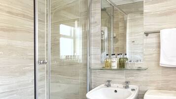 Un baño moderno con cabina de ducha de vidrio, lavamanos pedestal y retrete.