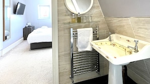 A modern bathroom with a large mirror, a sink with floral design, and a towel rack. - Dukes Folly Hotel (Southport)