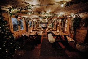 A cozy room with wooden walls, a fireplace, and a Christmas tree. - The Bull And Swan (Stamford)