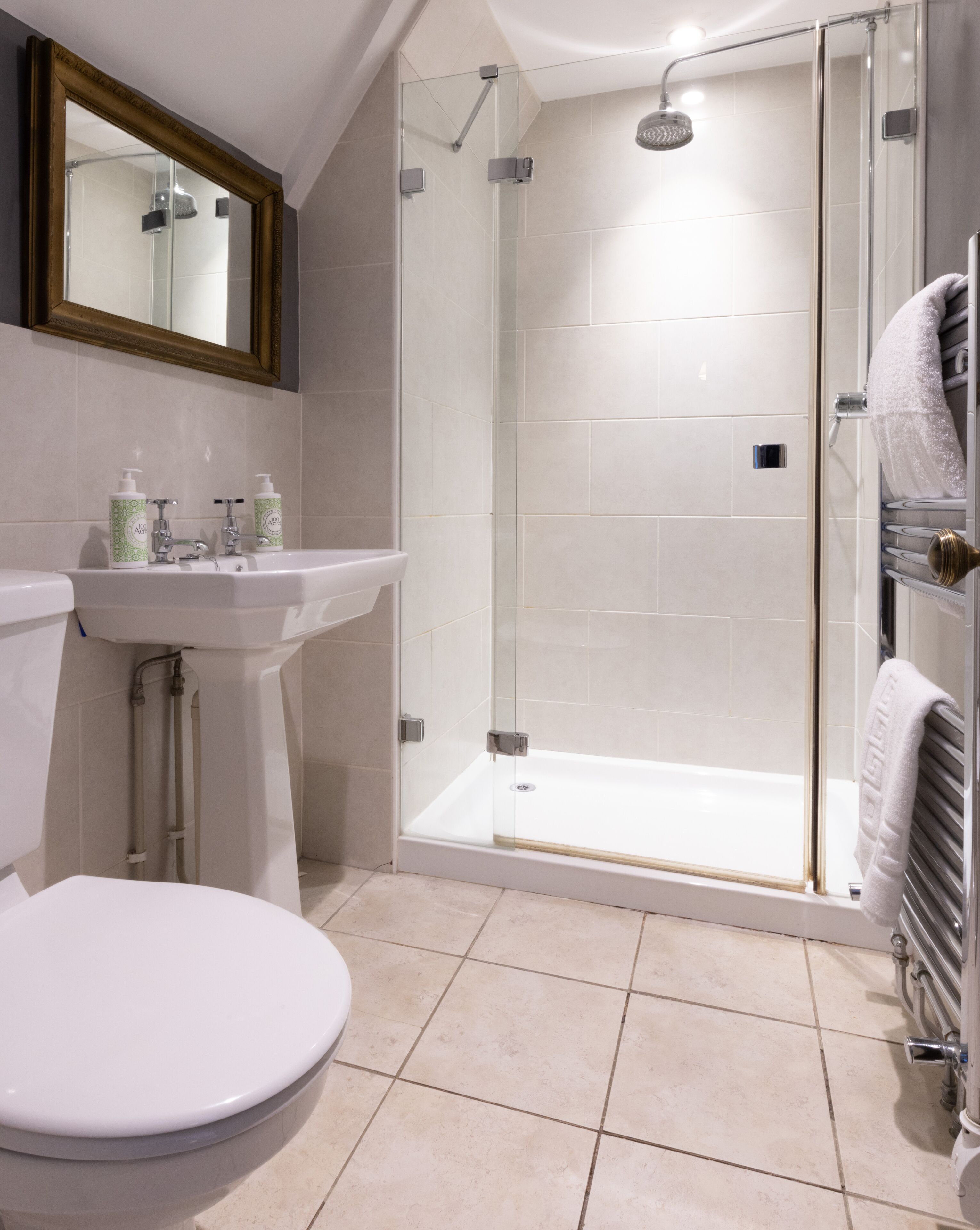 A modern bathroom with a glass-enclosed shower, a pedestal sink, and a toilet.