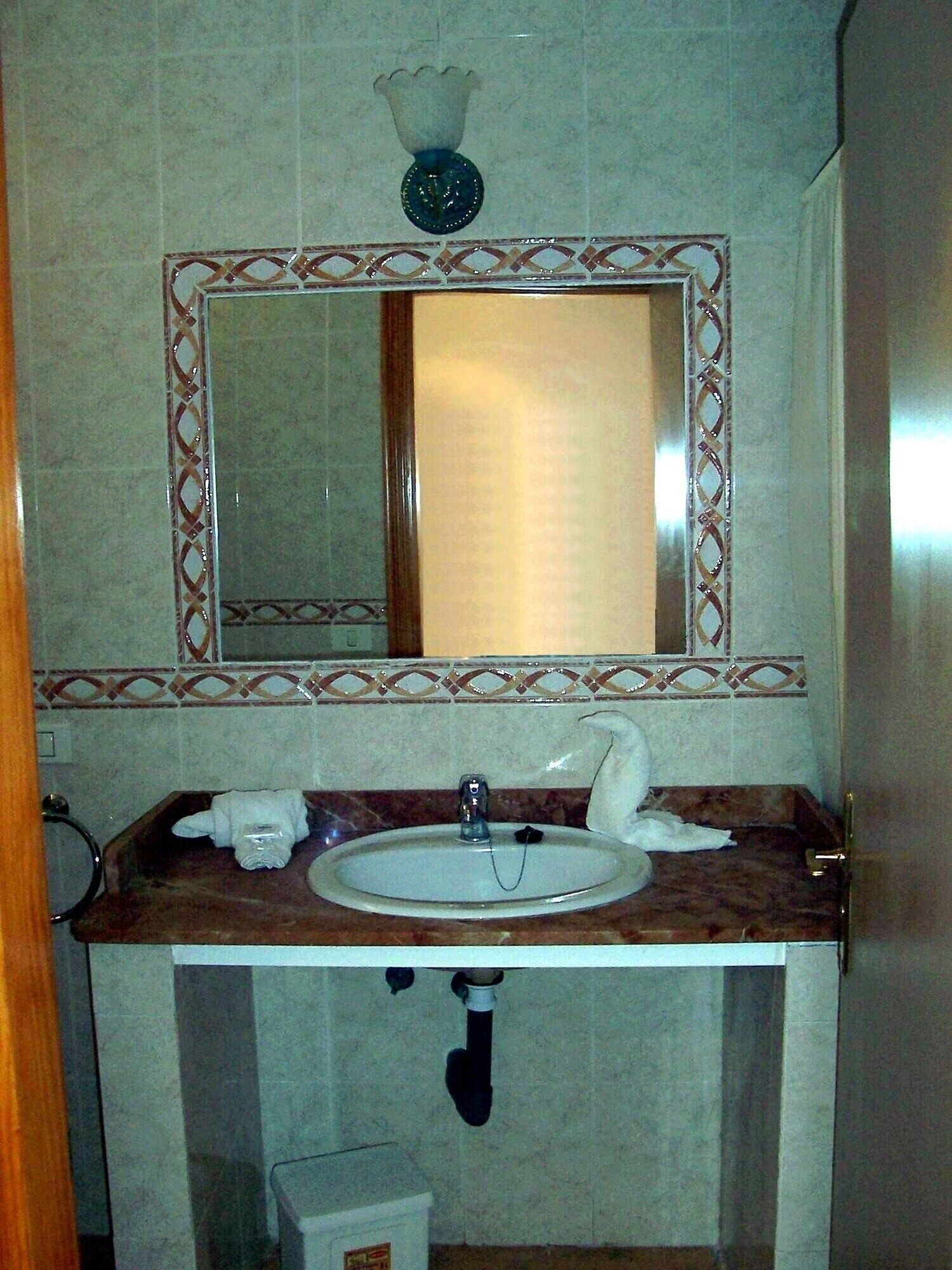 Un baño con lavamanos de mármol, un espejo con marco decorativo y un perchero para toallas.