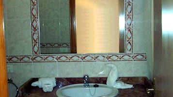 Un baño con lavamanos de mármol, un espejo con marco decorativo y un perchero para toallas.
