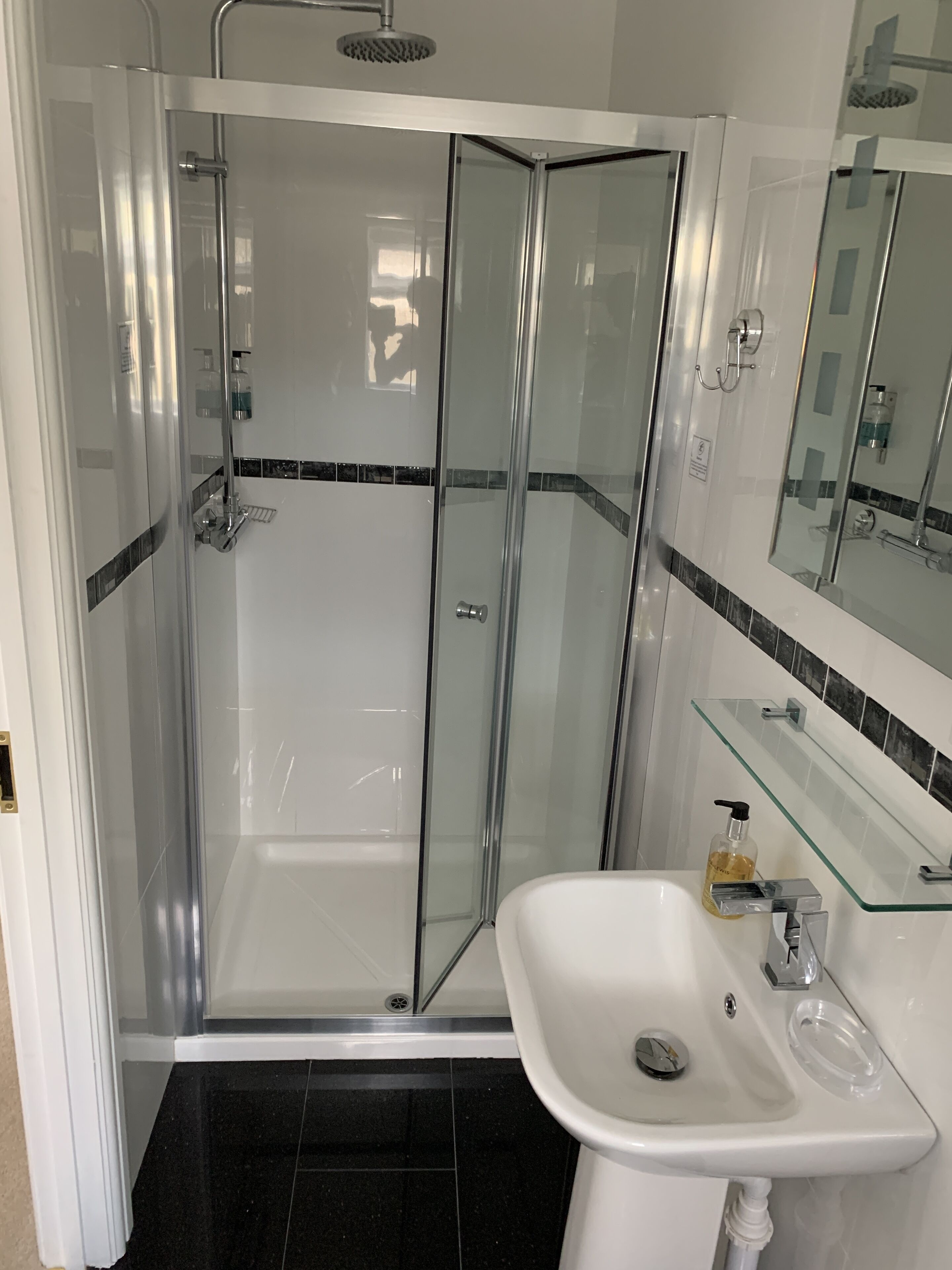 Ein modernes Badezimmer mit einer Duschkabine aus Glas, einem weißen Waschbecken und einer Glasablage.