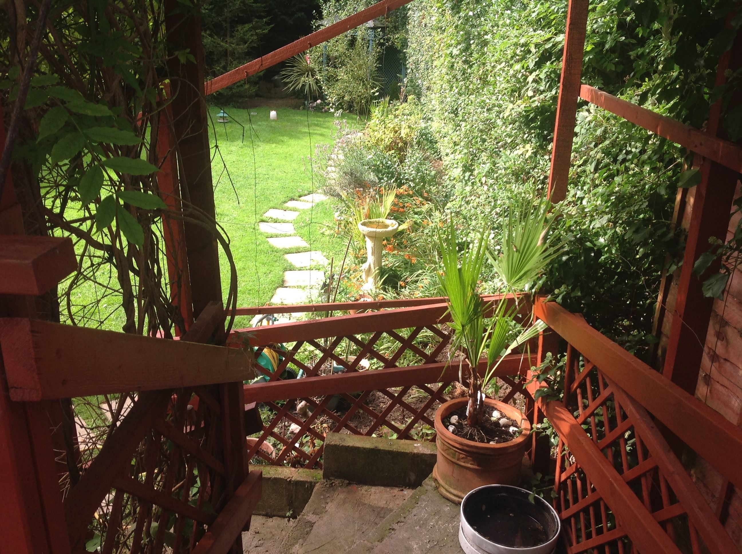 Un balcon en bois donnant sur un jardin.