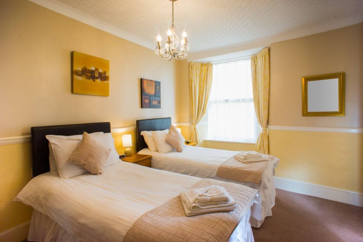 A hotel room with two beds, a chandelier, and artwork on the walls.