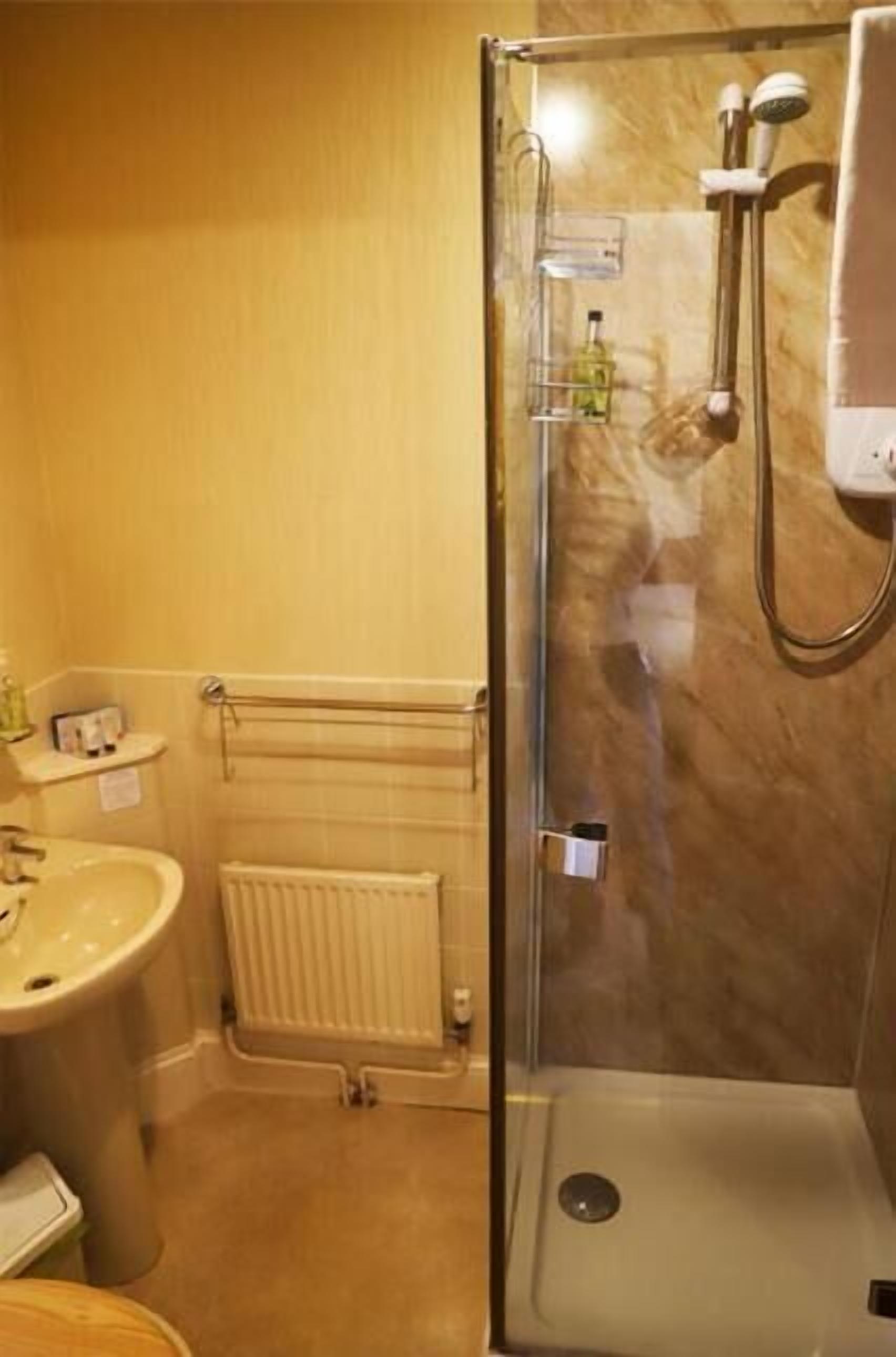 A bathroom with a glass-enclosed shower, a sink, and a toilet.