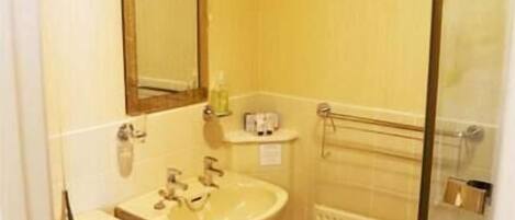 A compact bathroom with a toilet, sink, and a glass shower enclosure.